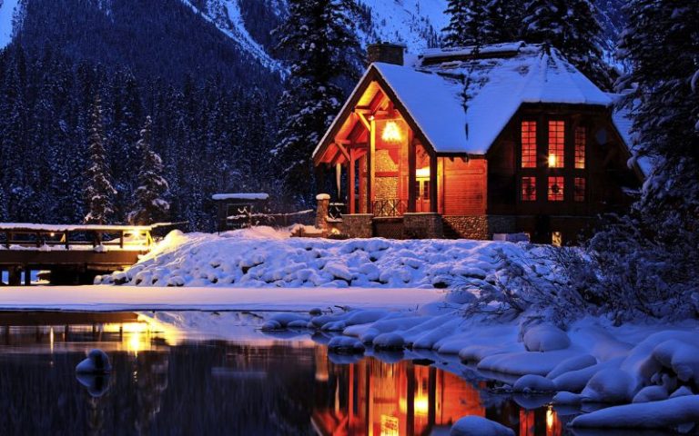 Chalet en bois éclairé au bord d'un lac dans la pénombre